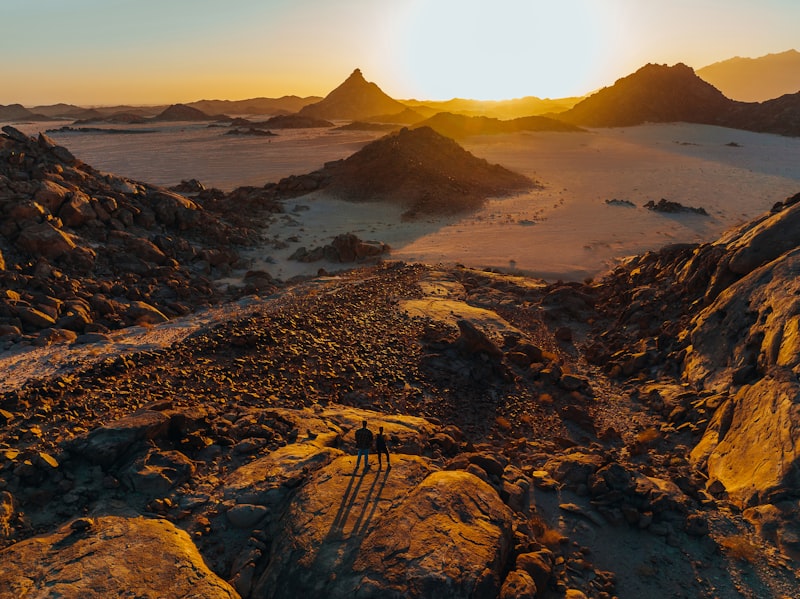Cinematic wide shot of golden sand dunes under a clear blue sky, showing vast desert landscapes and ripples in the sand, photorealistic, 8k resolution